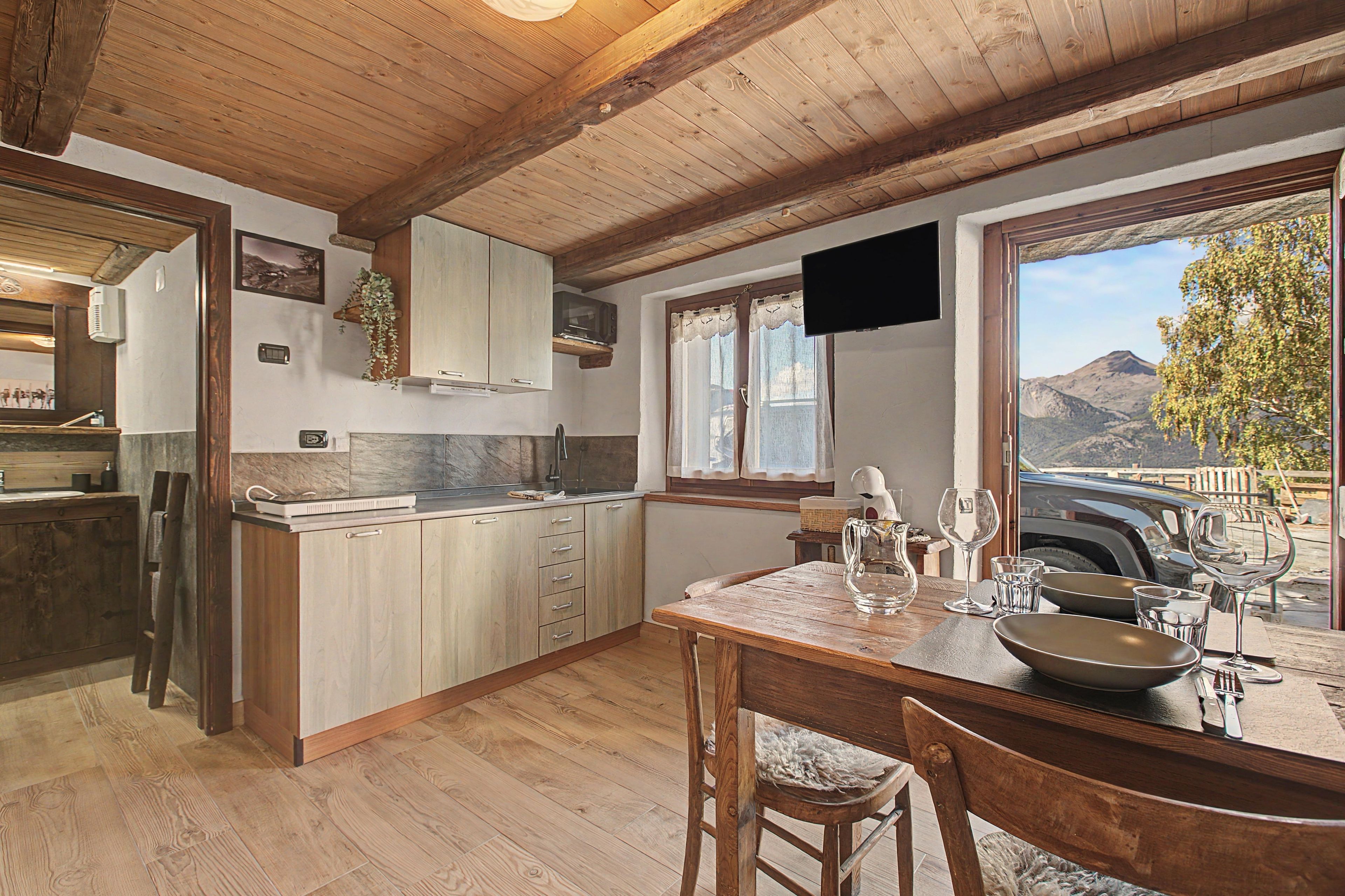 Una cocina rústica con armarios de madera, un respuesto de piedra y un comedor con vistas a montañas.