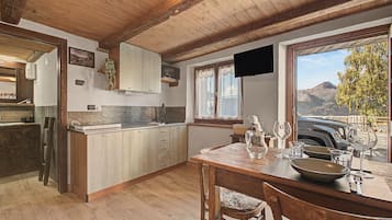 Una cocina rústica con armarios de madera, un respuesto de piedra y un comedor con vistas a montañas.