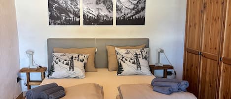 A cozy room with a bed, wooden furniture, and mountain landscape artwork.
