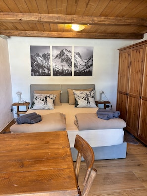 A cozy room with a bed, wooden furniture, and mountain landscape artwork.