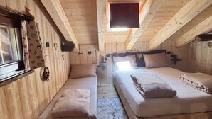 Una cabaña de madera con dos camas, un ventanal y un tragaluz.