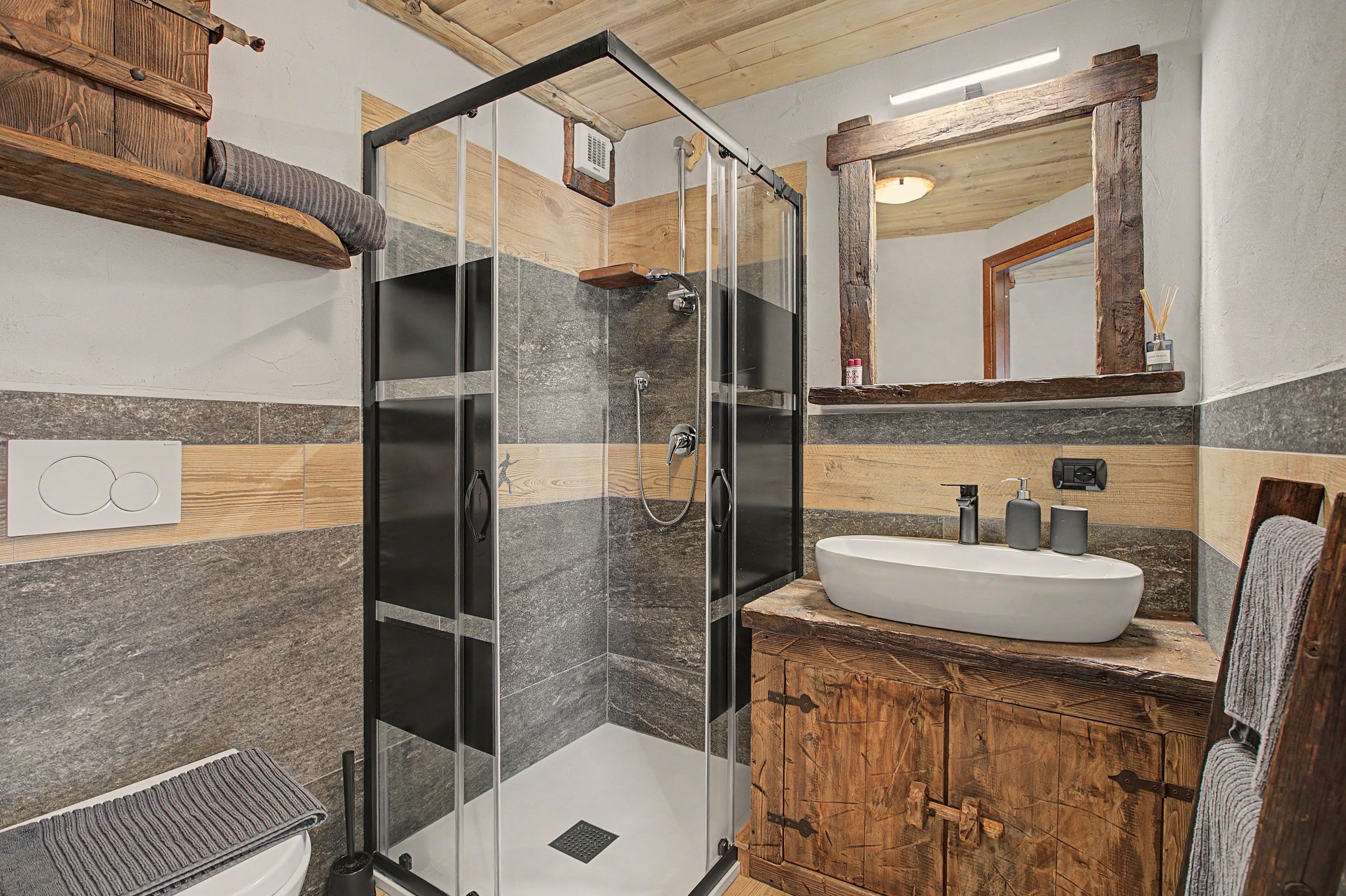 A modern bathroom with a glass shower enclosure, a wooden vanity, and a large mirror.