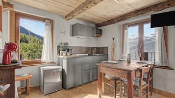 Una cocina equipada con microondas, refrigerador y una mesa de comedor de madera con sillas.