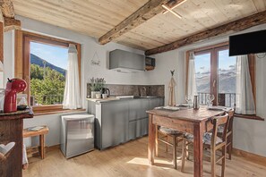 Una cocina equipada con microondas, refrigerador y una mesa de comedor de madera con sillas.