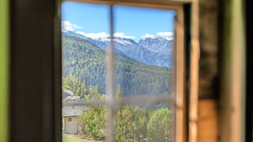 A window with a view of a mountainous landscape, a small building, and a clear sky.