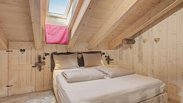 A bedroom with a skylight, wooden walls, a bed with white bedding, and heart-shaped decorations.