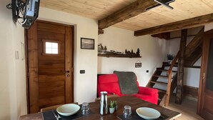 Un comedor con mesa de madera, sillas y un sofá rojo.