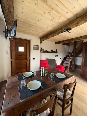 A dining area with a wooden table, chairs, and a red sofa.