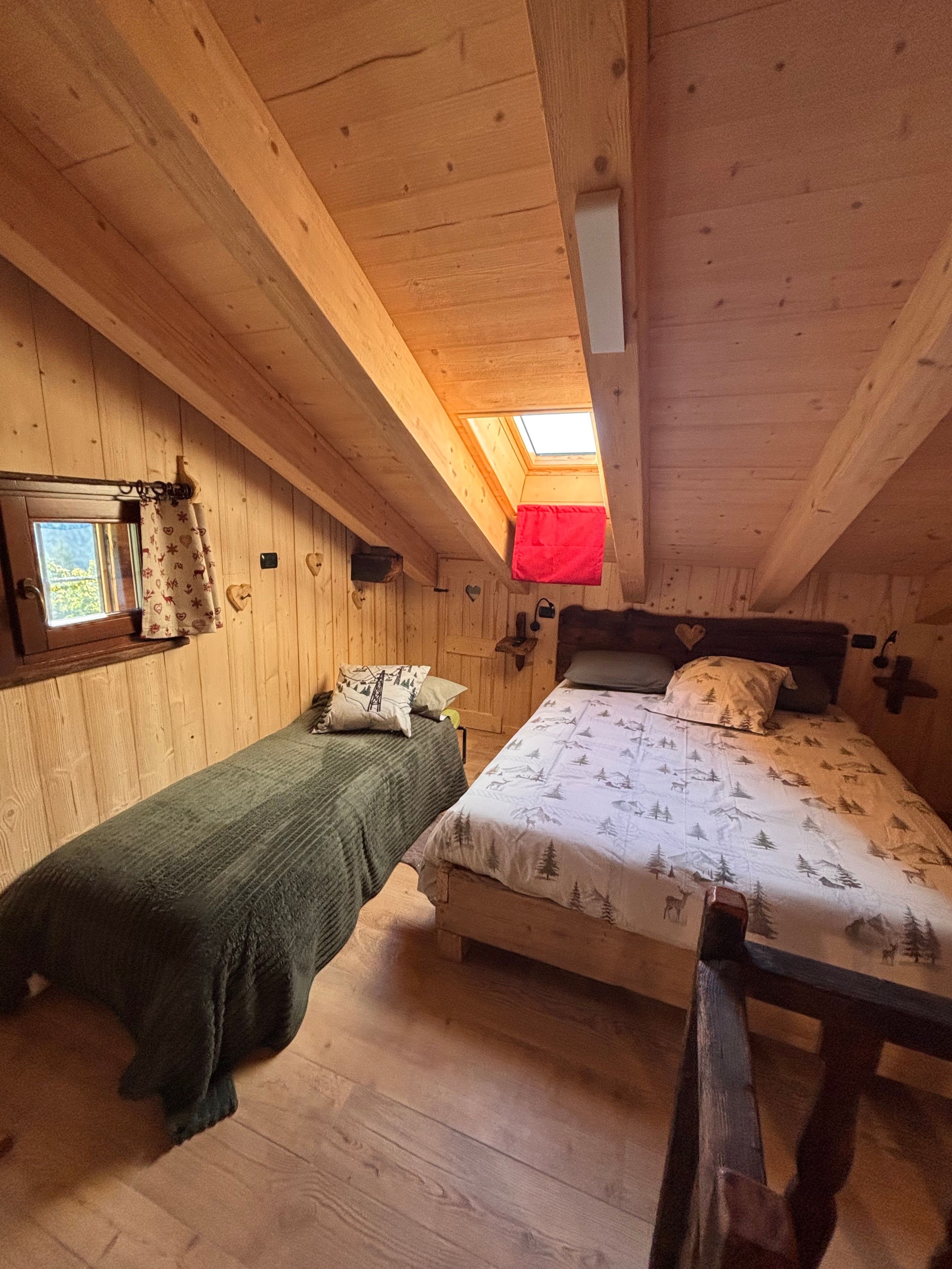 A cozy cabin bedroom with two beds, a skylight, and wooden walls.