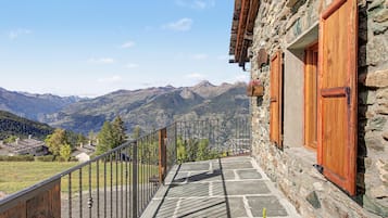 A stone building with a balcony overlooking a mountainous landscape.