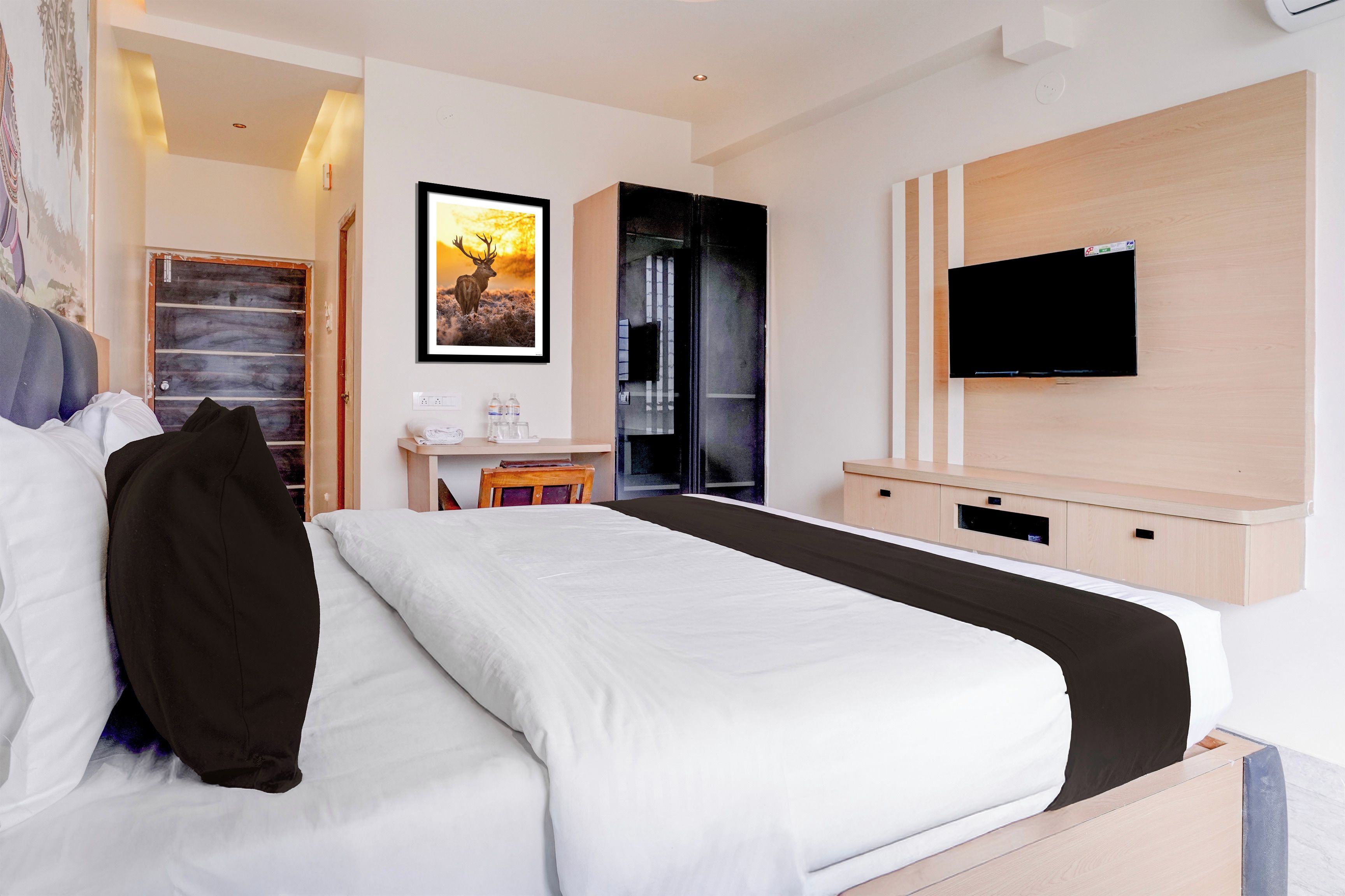 Une chambre d’hôtel avec un lit, un bureau, une télévision et un tableau au mur.