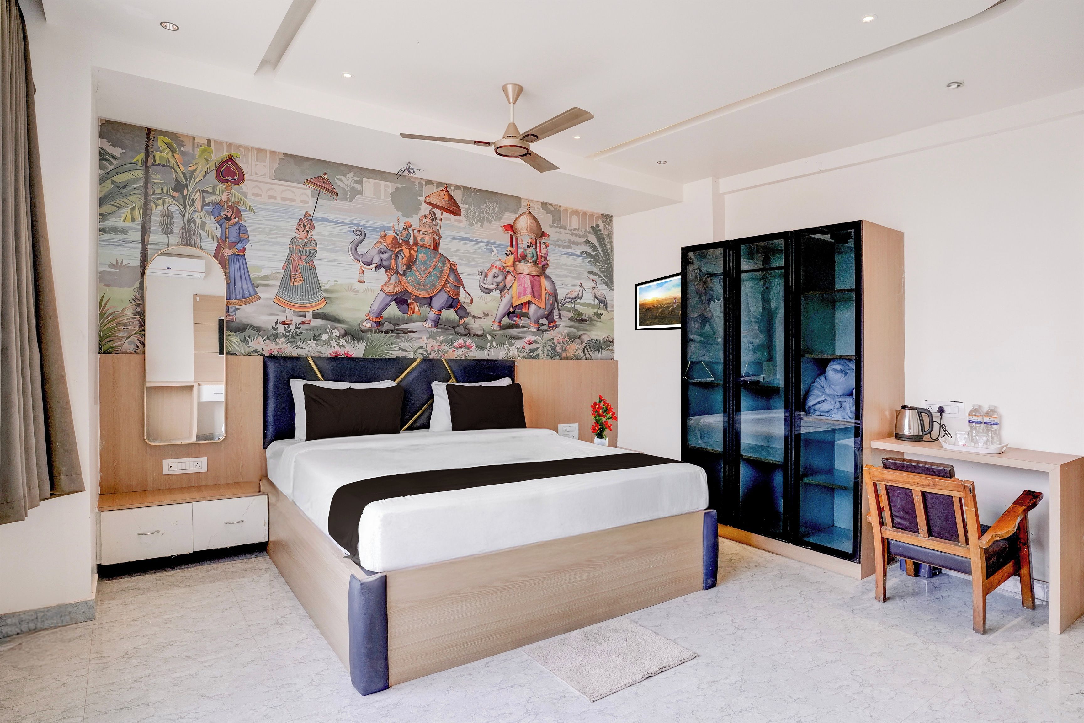 A hotel room with a large bed, a desk, a wardrobe, and a ceiling fan.