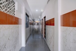 Un largo y estrecho pasillo con paredes de mármol y suelo gris, que conduce a varias puertas.