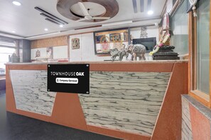 A reception desk with a sign indicating it is a company-serviced location. - Super Townhouse Oak Dharwad New Bus (Dharwad)