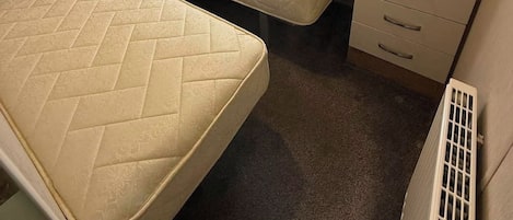 Habitación compacta con cama, un pequeño escritorio, armario y ventana con cortinas.