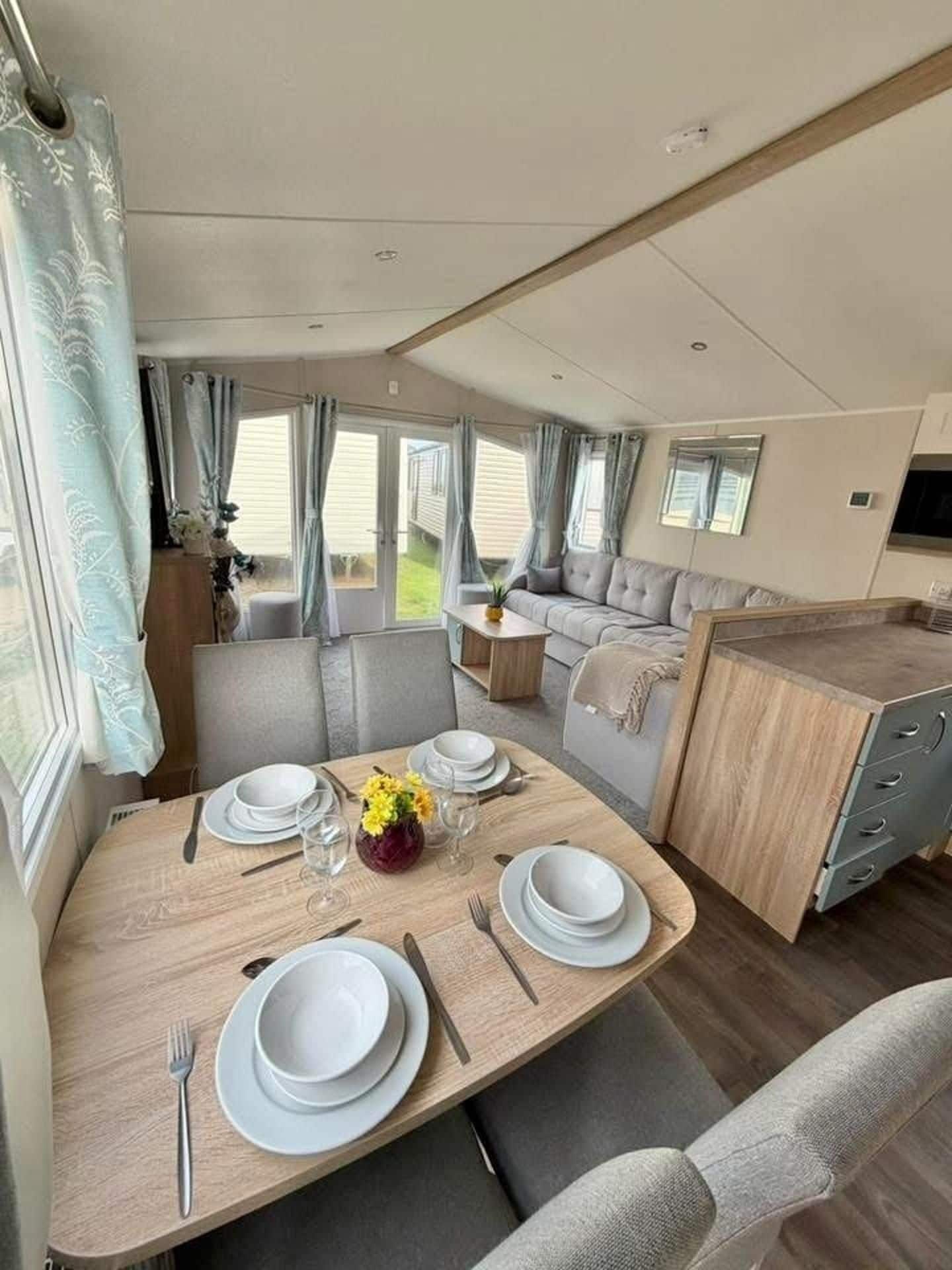 A compact RV interior with a dining area, a sofa, and a kitchenette.