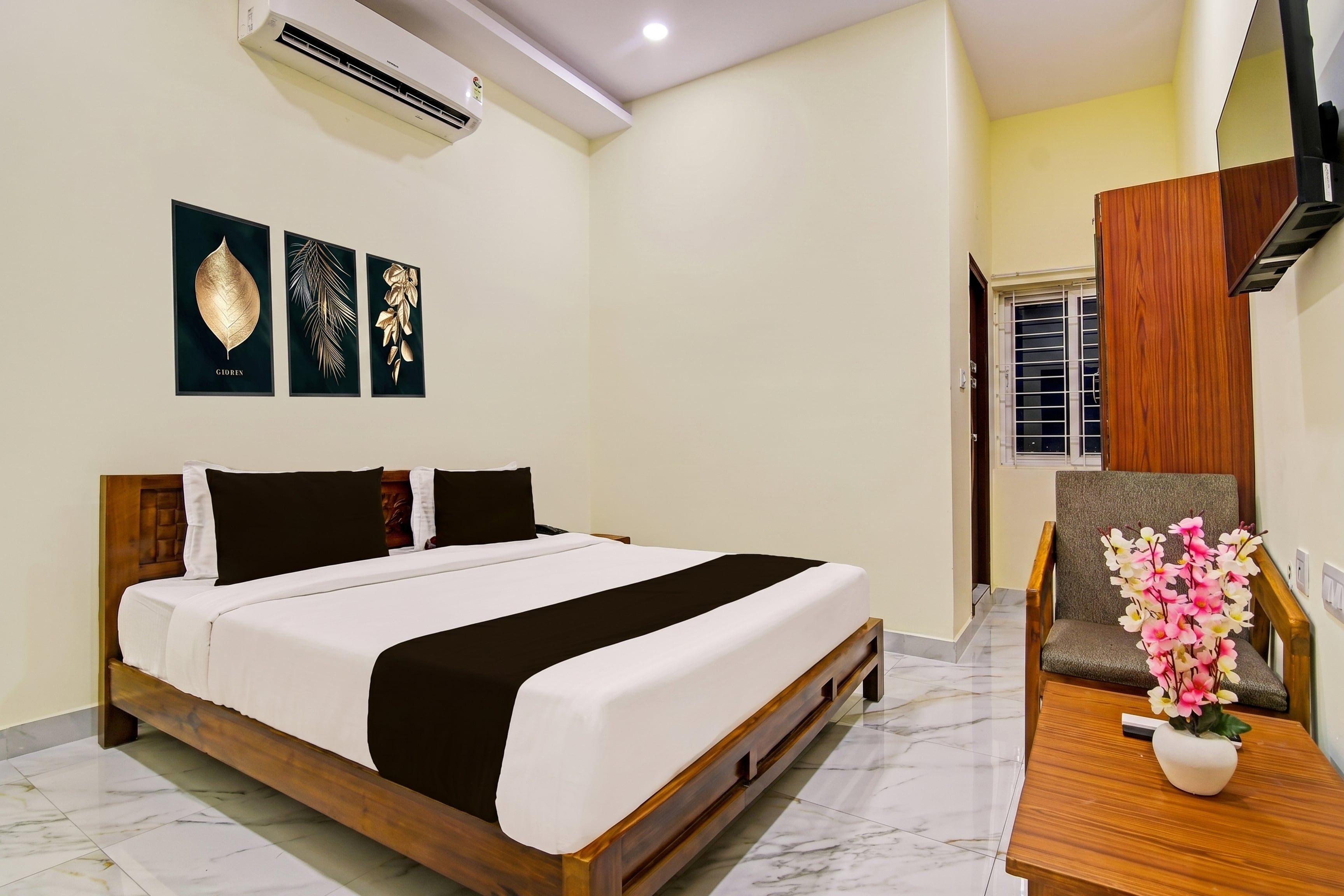 Ein Hotelzimmer mit einem Bett, einem Schreibtisch und einem Stuhl. Eine Klimaanlage ist an der Wand angebracht.