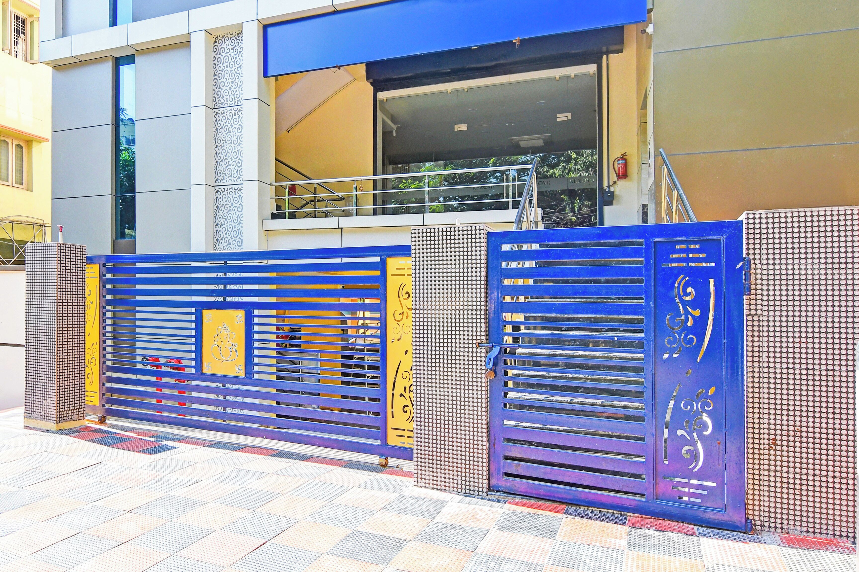 A building entrance with a blue and yellow gate, a staircase, and a fire extinguisher.