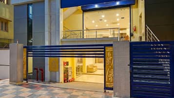 Entrada de hotel con una verja azul, una rampa accesible para sillas de ruedas y un extintor visible.