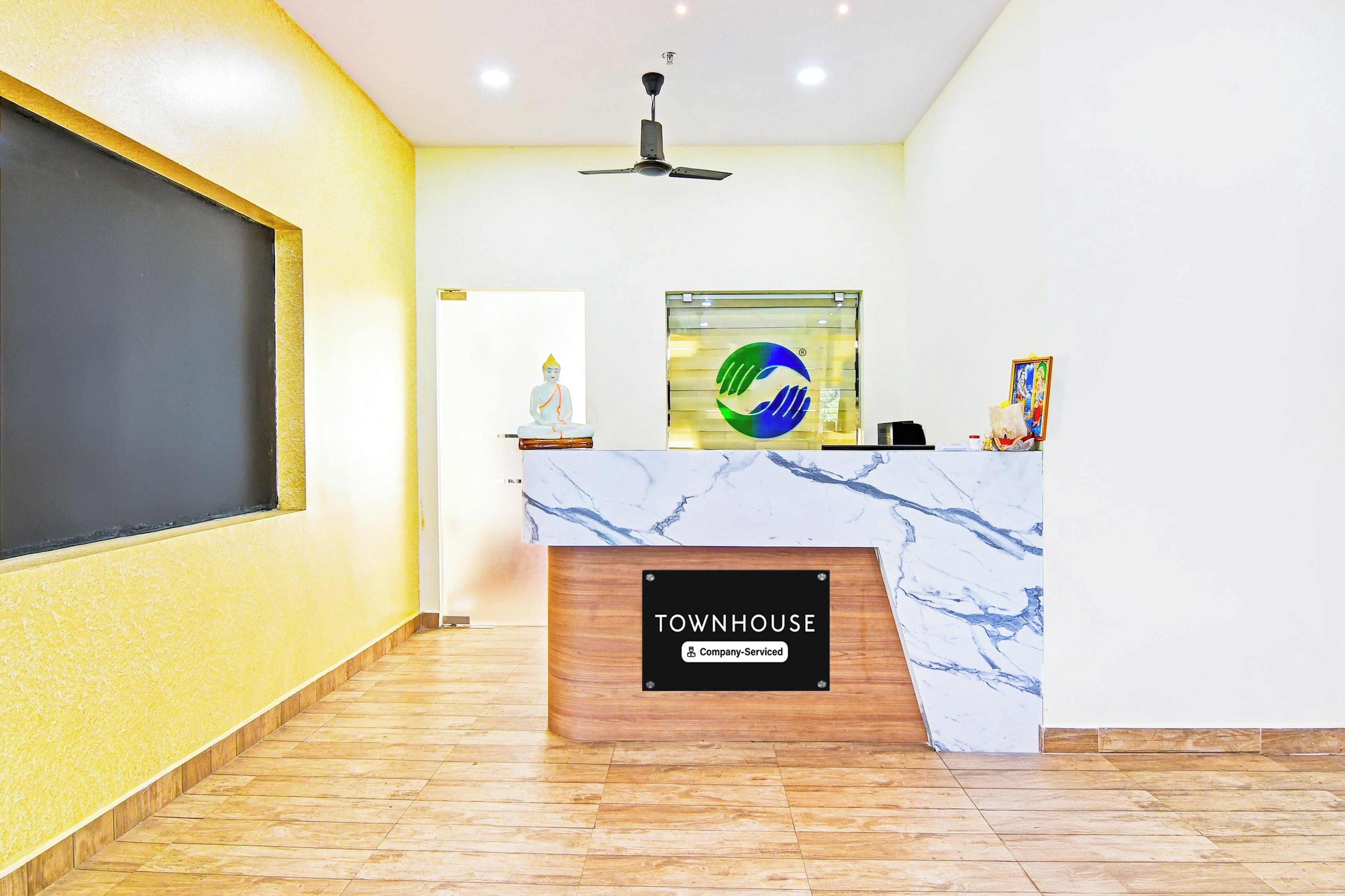 Un comptoir d’accueil avec un plateau en marbre, une enseigne fournie par l’entreprise et un logo placé au-dessus.