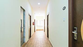 A corridor with doors on both sides, a fire extinguisher, and a window at the end.