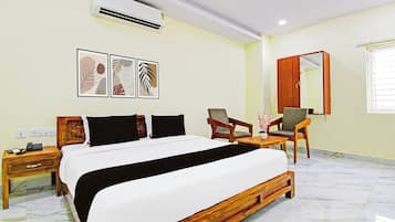 Habitación de hotel con cama, escritorio con teléfono, silla, espejo y decoración en la pared.
