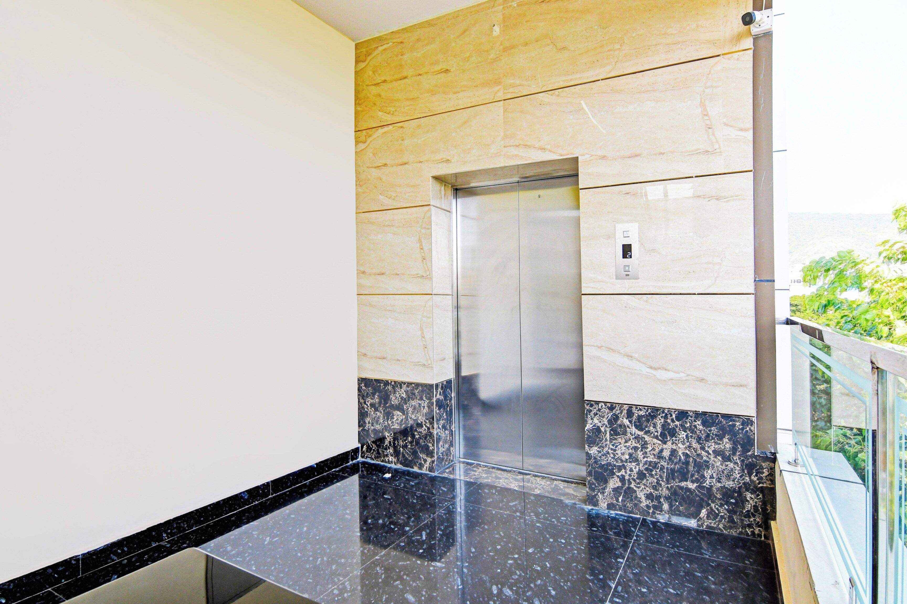 A modern elevator with a marble wall and a glass railing.