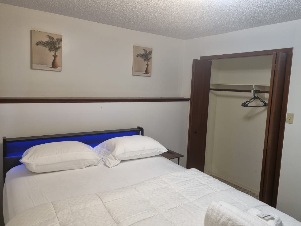 Habitació d'hotel amb un llit, un armari i dues fotografies penjades a la paret.