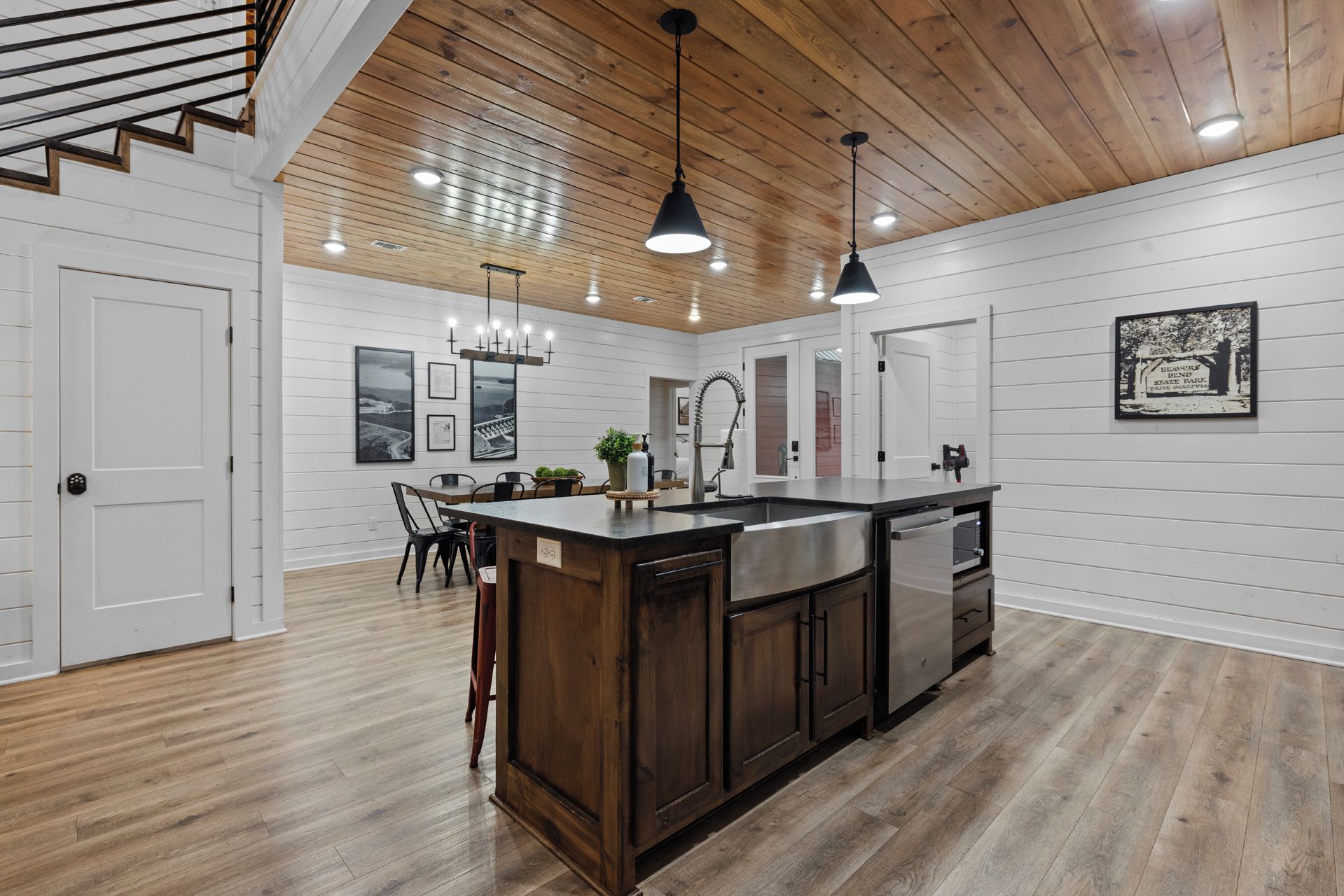 A spacious kitchen with a central island, wooden ceiling, and pendant lighting.