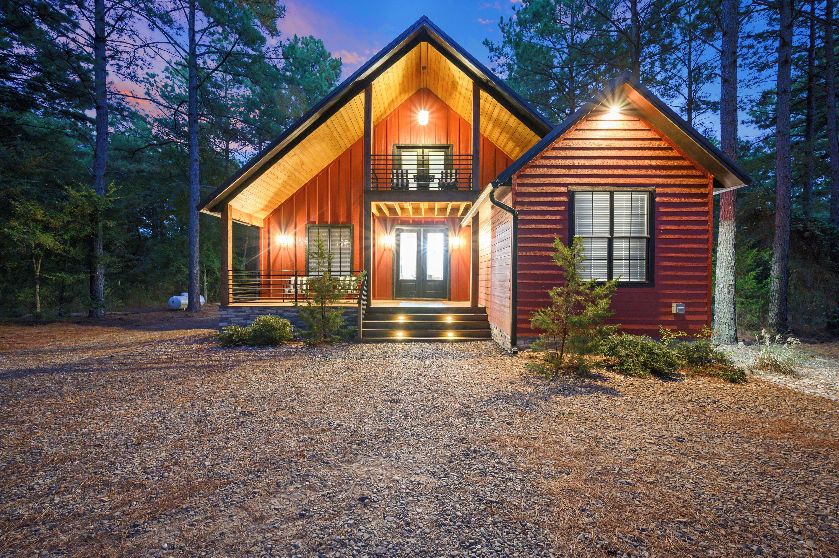 A two-story log cabin with a front porch, a balcony, and a separate garage.