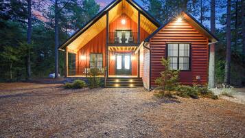 A two-story log cabin with a front porch, a balcony, and a separate garage.