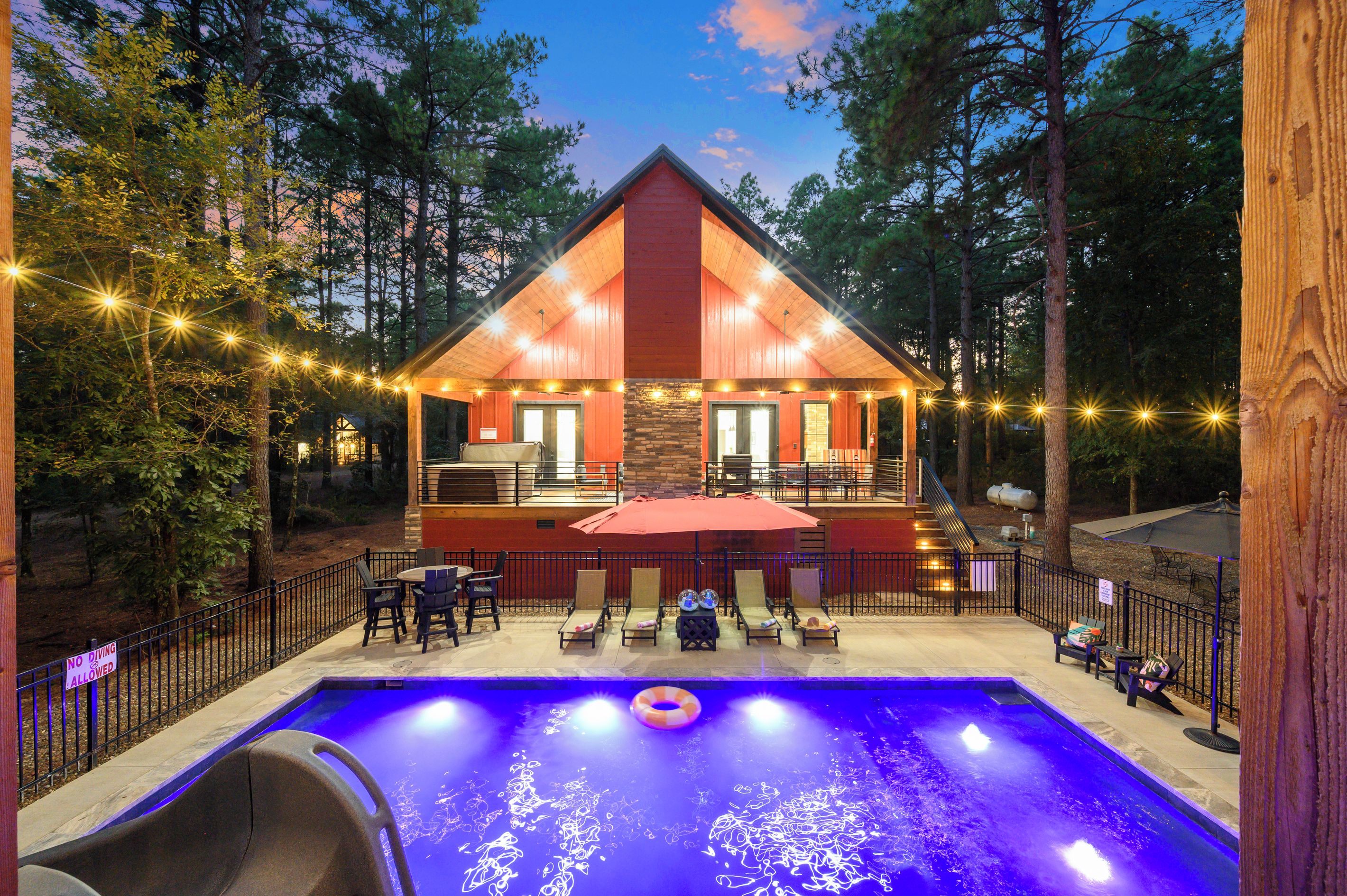 A cabin with a pool, outdoor seating, and string lights.