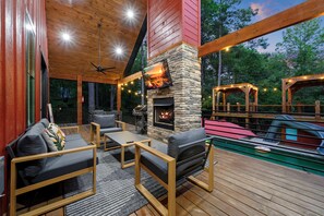 Eine Terrassenanlage im Freien mit Kamin aus Stein, Sitzgelegenheiten und einem Pool.