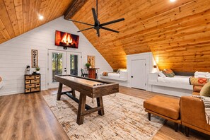 Ein gemütliches Loft-Zimmer mit Tischfußball, einem Bett, einer Couch und einem Deckenventilator.