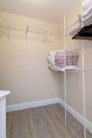 A laundry room with metal shelving units, a wooden floor, and a white wall. - Spacious 2br-2ba townhome located in Saddlebrook (Zephyrhills)