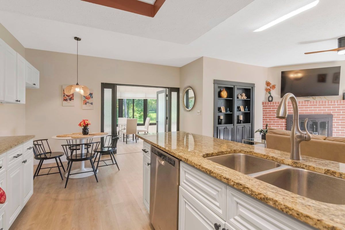 A modern kitchen with granite countertops, stainless steel appliances, and a dining area with a round table and chairs.