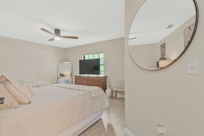 A bedroom with a bed, a dresser, a television, a ceiling fan, and a large mirror. - Spacious 2br-2ba townhome located in Saddlebrook (Zephyrhills)