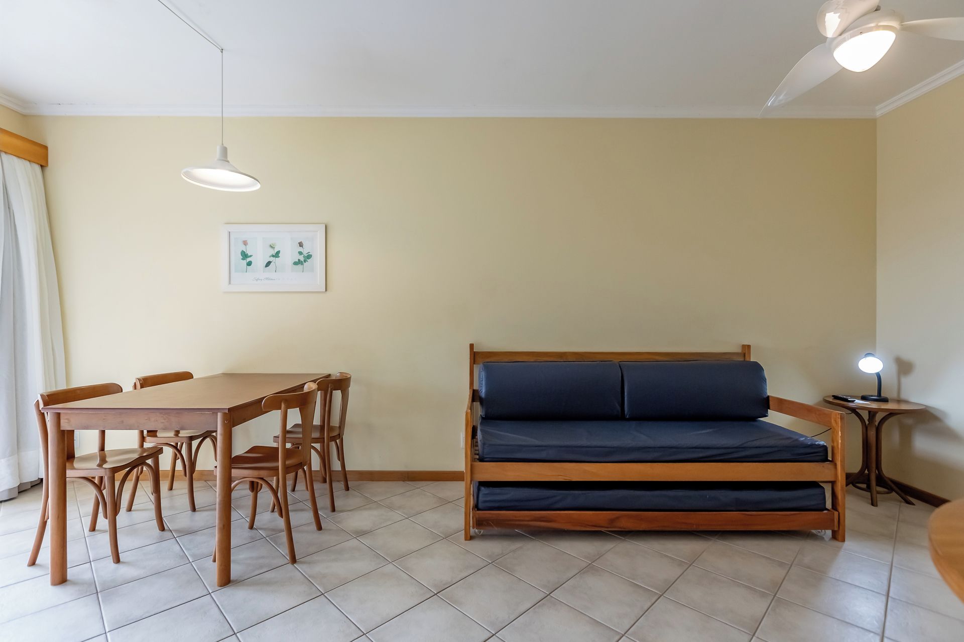 Una habitación con una cama, una mesa de comedor con sillas, un cuadro en la pared y una lámpara en el techo.