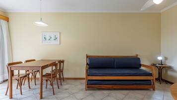 Una habitación con una cama, una mesa de comedor con sillas, un cuadro en la pared y una lámpara en el techo.