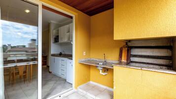 A compact kitchen with a built-in oven, a sink, and a dining area with chairs.