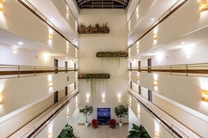 Un atrium à plusieurs niveaux avec un espace de repos central, des plantes en pot et un panneau indiquant « Clube Candelas ».