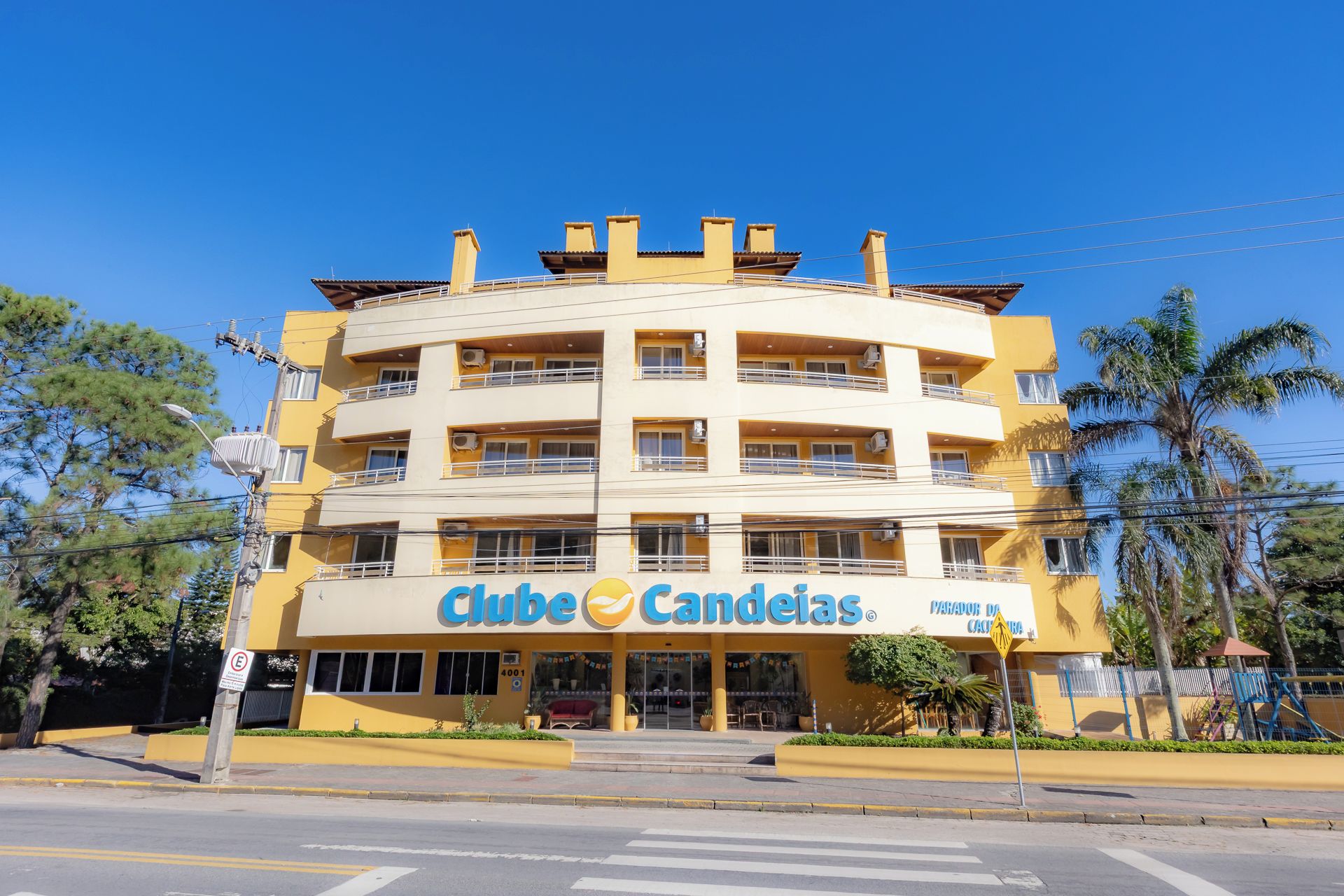 Een hotel met meerdere verdiepingen, een gele gevel, balkons en een bord met de tekst 'Club Candelas'.
