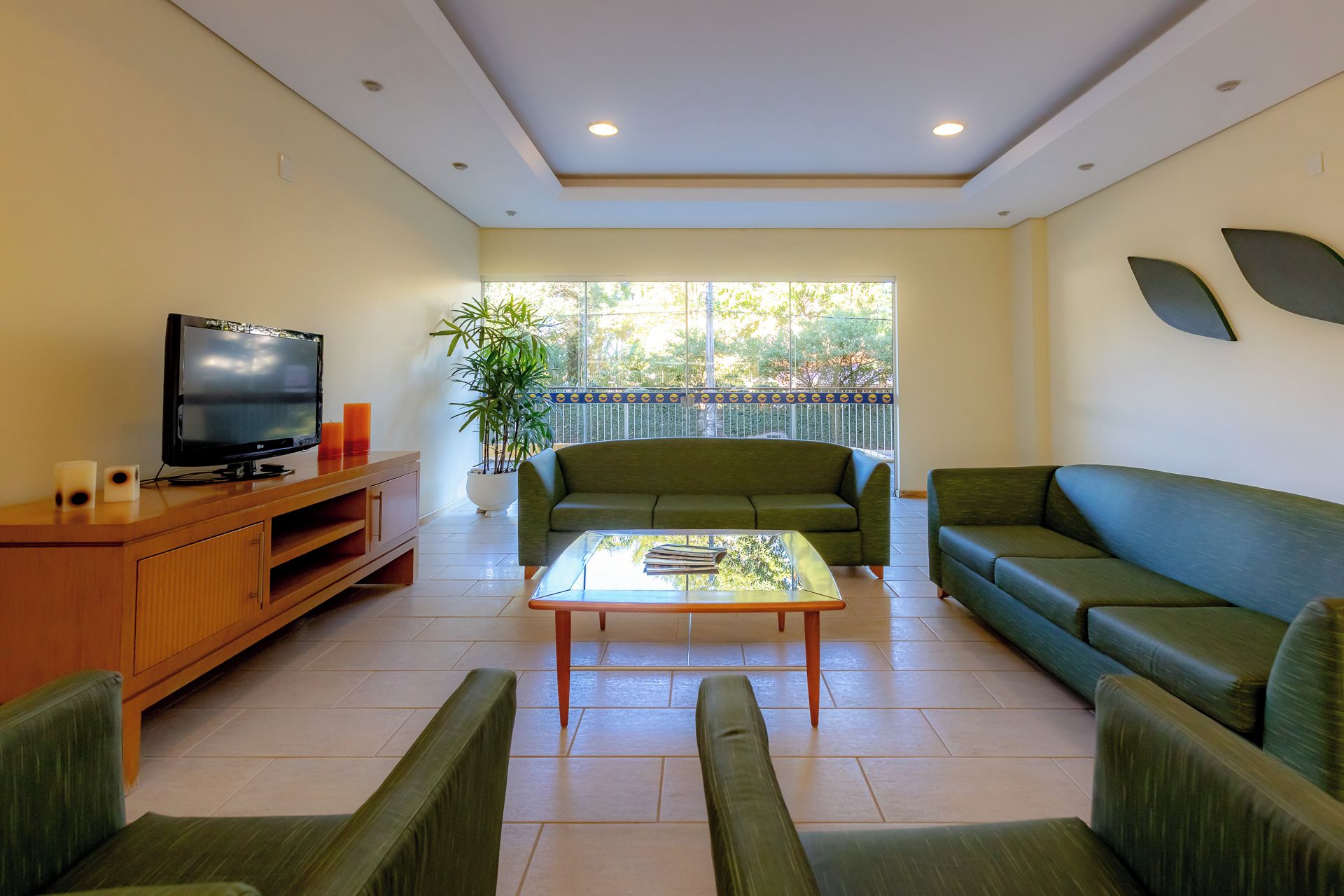 A living room with a television, sofa, coffee table, and a potted plant.