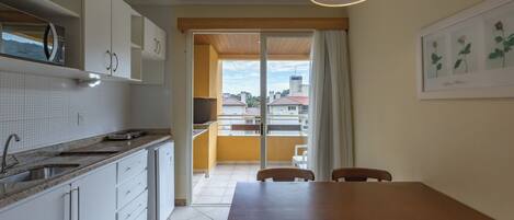 A kitchen with white cabinets, a sink, and a dining area with a table and chairs.