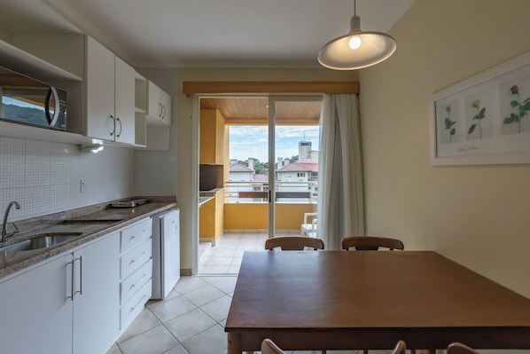 A kitchen with white cabinets, a sink, and a dining area with a table and chairs.