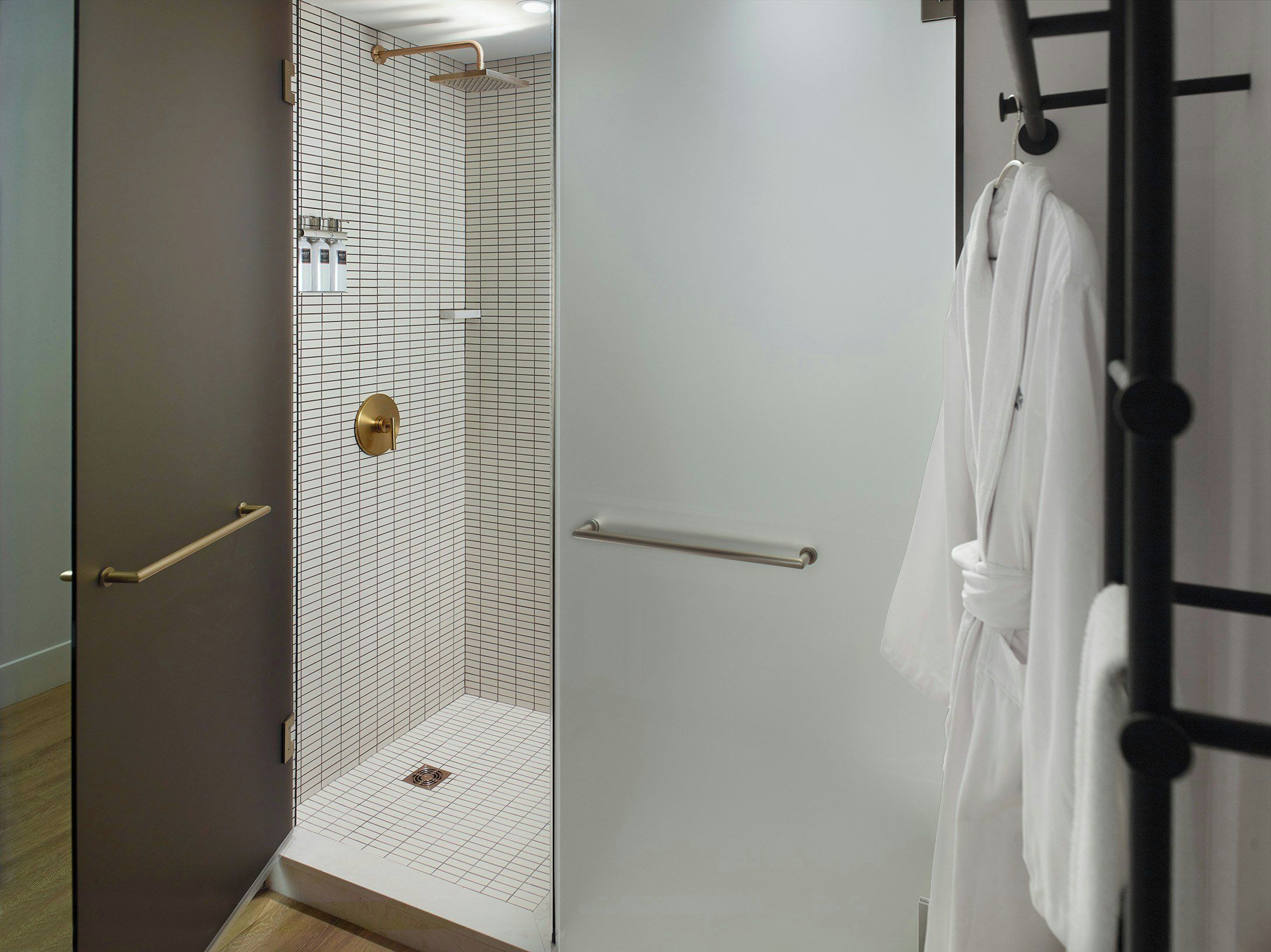 A modern bathroom with a walk-in shower, a towel rack, and a door with a handle.