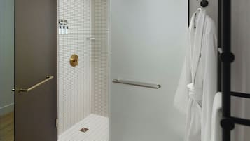 A modern bathroom with a walk-in shower, a towel rack, and a door with a handle.