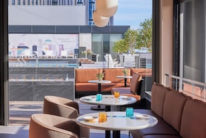 A rooftop lounge with seating and tables, a pool in the background, and a cityscape view. - Omni Boston Hotel at the Seaport Artist Tower Experience (Boston)