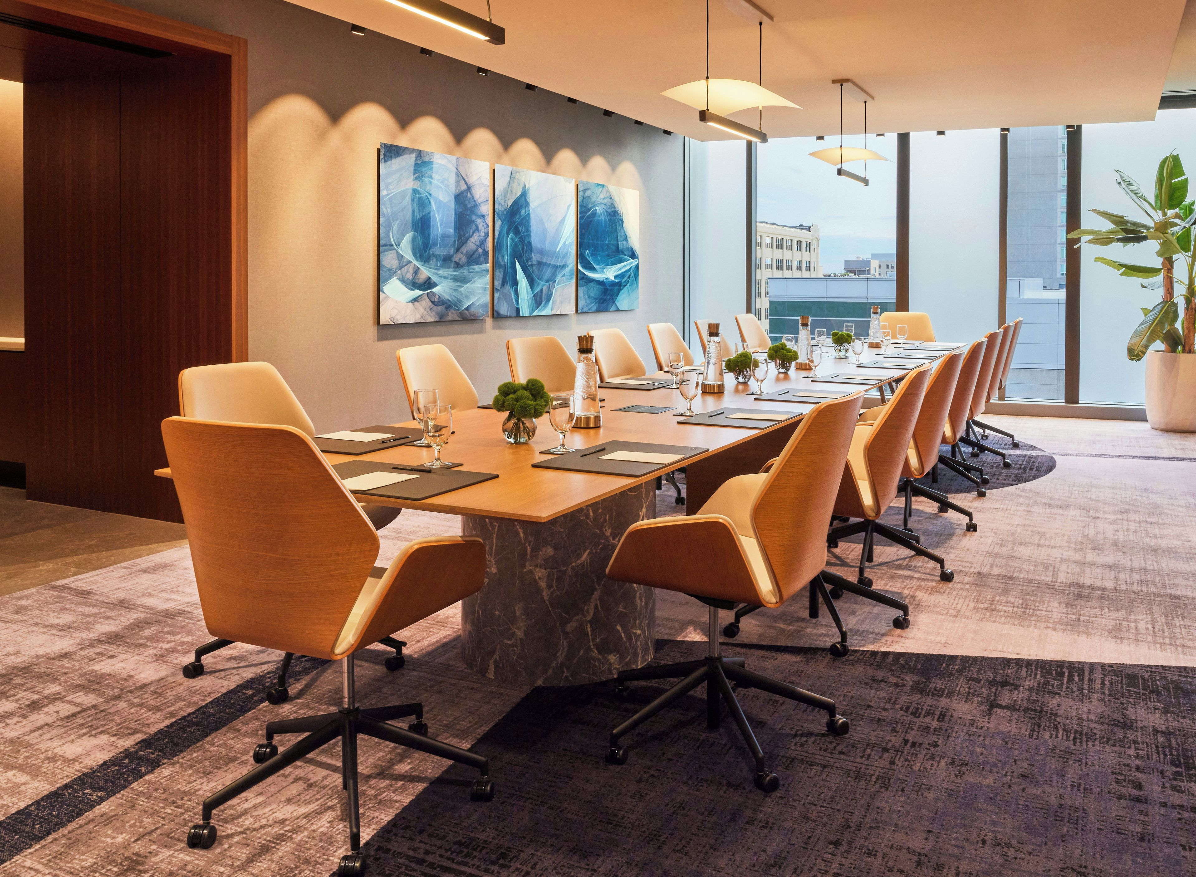 A conference room with a long table, chairs, and a city view.