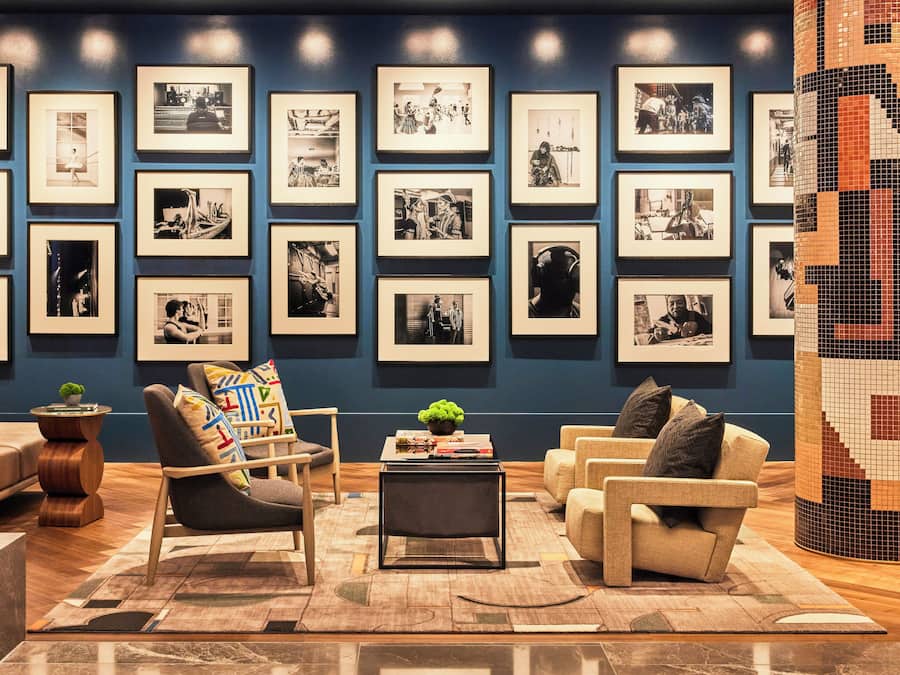 Uma sala de estar moderna com uma parede azul de destaque, várias fotografias em preto e branco emolduradas e móveis contemporâneos.
